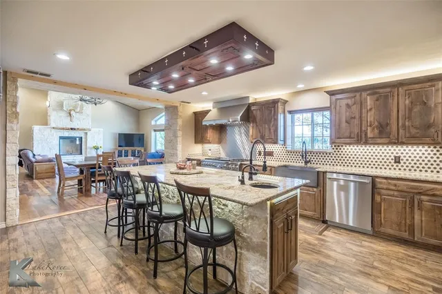 a kitchen with stainless steel appliances a table chairs sink and cabinets