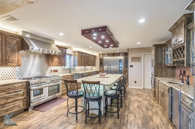a kitchen with stainless steel appliances a dining table chairs stove and wooden floor