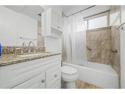 a bathroom with a granite countertop sink a toilet and bathtub