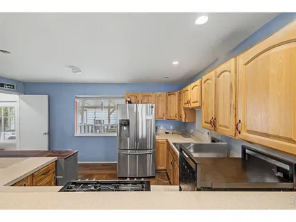 a kitchen with stainless steel appliances granite countertop a refrigerator a sink and a stove with wooden floor
