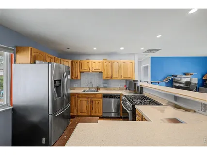 a kitchen with stainless steel appliances granite countertop a refrigerator a sink and white cabinets