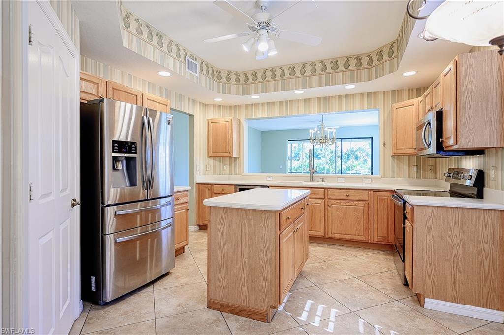 5805 Grande Reserve Way, Unit 1102 Naples, FL 34110 - Photo 6 of 38 a kitchen with stainless steel appliances granite countertop a refrigerator a sink a stove a microwave and island