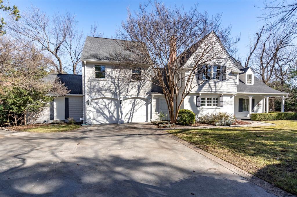 View of front of house featuring asphalt driveway, covered porch, a garage, a front lawn, and roof with shingles