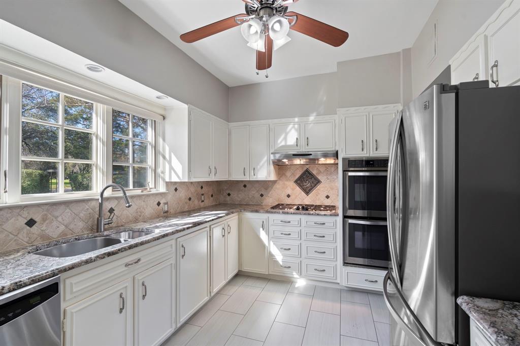 8530 Jourdan Way Dallas, TX 75225 - Photo 11 of 39 Kitchen with stainless steel appliances, light stone countertops, and white cabinetry