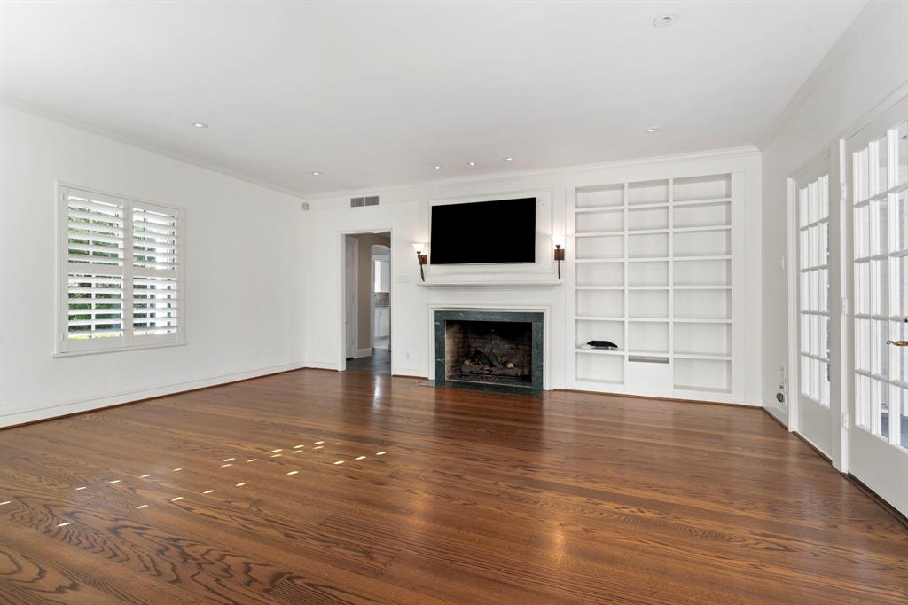 8530 Jourdan Way Dallas, TX 75225 - Photo 4 of 39 Unfurnished living room with built in features, a fireplace with flush hearth, dark wood-type flooring, and ornamental molding