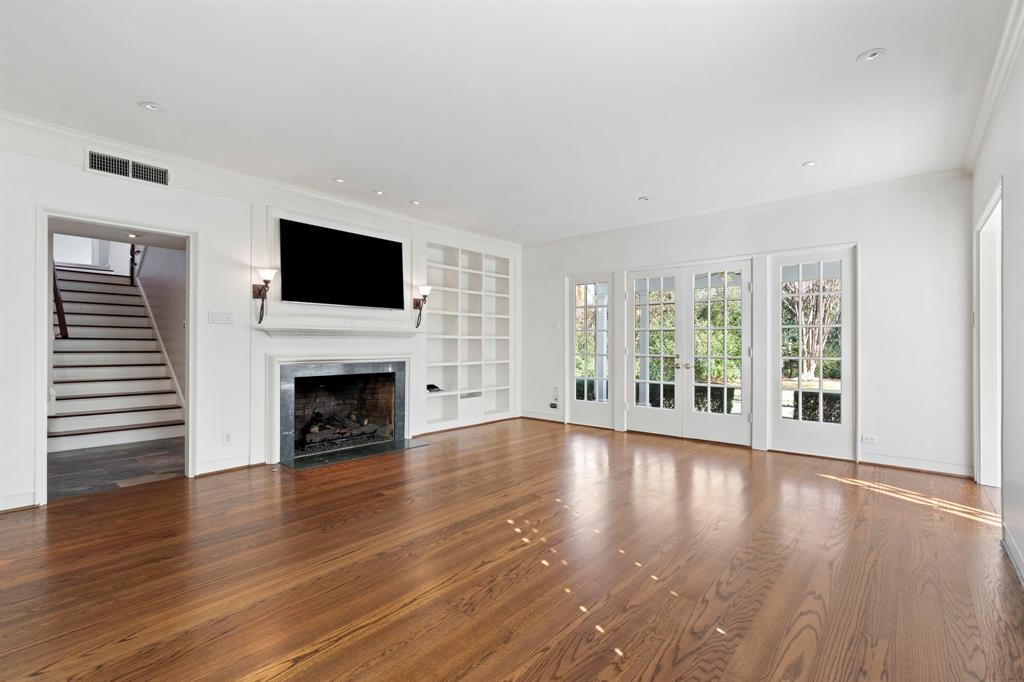 8530 Jourdan Way Dallas, TX 75225 - Photo 6 of 39 Unfurnished living room with french doors, plenty of natural light, dark wood-style floors, built in features, and crown molding