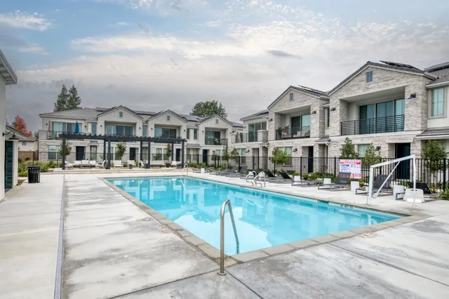 a view of a white house next to a yard with potted plants