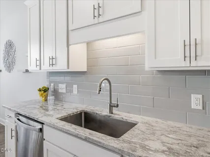 a kitchen with granite countertop a sink and a white wooden cabinets