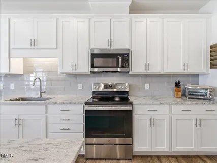 a kitchen with granite countertop white cabinets and stainless steel appliances