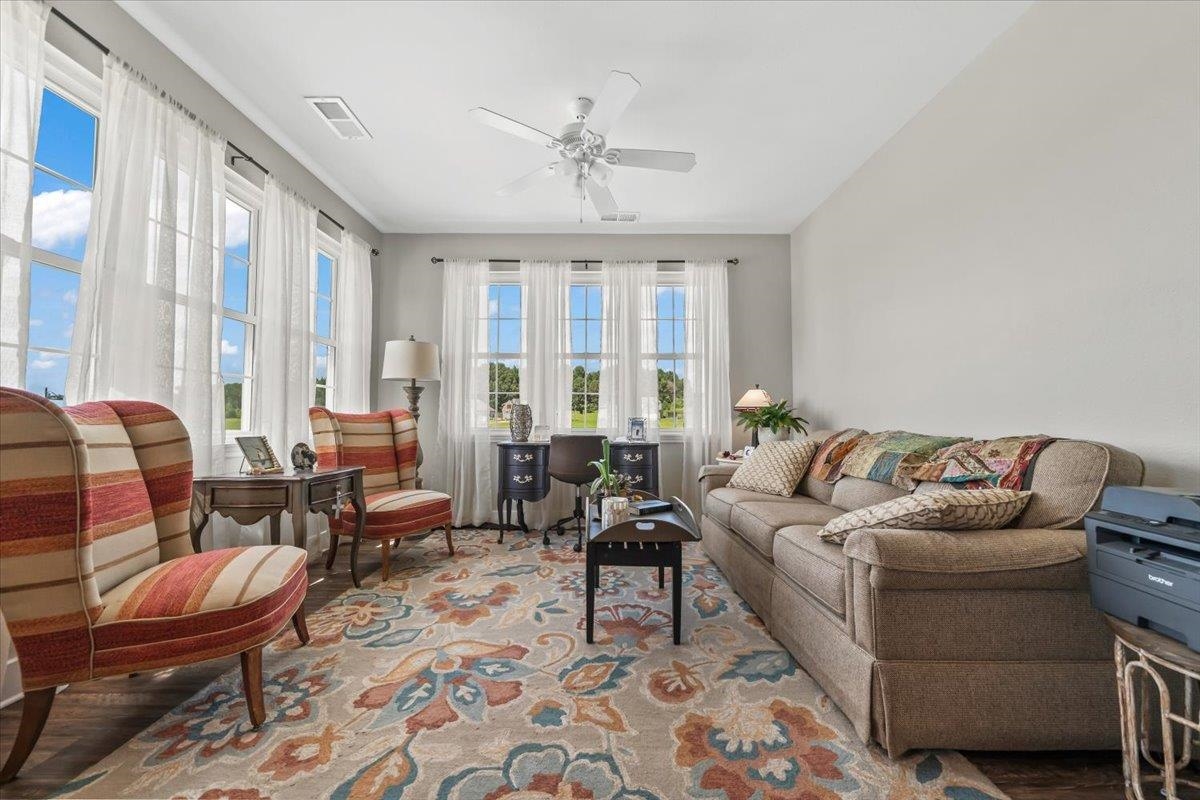 415 Abbey Road, Unit D Munford, TN 38058 - Photo 5 of 35 Spacious room featuring multiple large windows, wood-finish flooring, light gray wall paint, and a ceiling fan