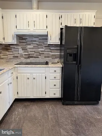 a kitchen with granite countertop a refrigerator stove and cabinets