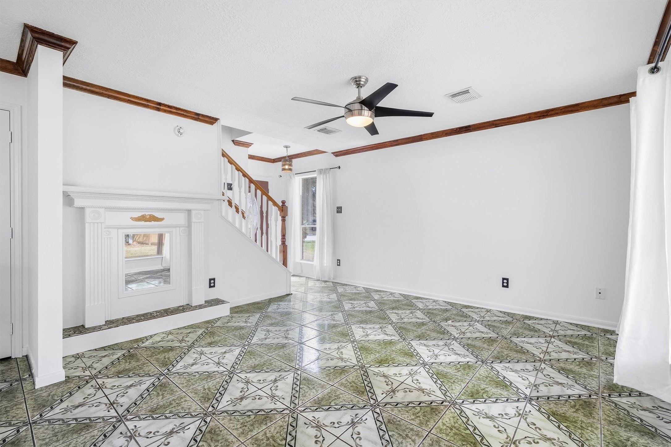 5426 Bourgeois Road Houston, TX 77066 - Photo 10 of 43 Pleasing living area featuring unique patterned tile flooring, a decorative fireplace, and a modern ceiling fan, complemented by natural light streaming through large windows.