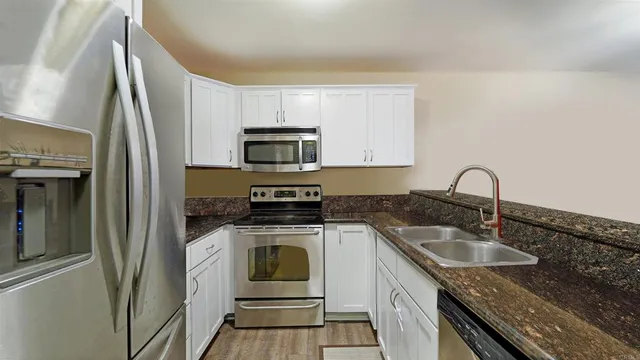 a kitchen with granite countertop a sink stove and refrigerator