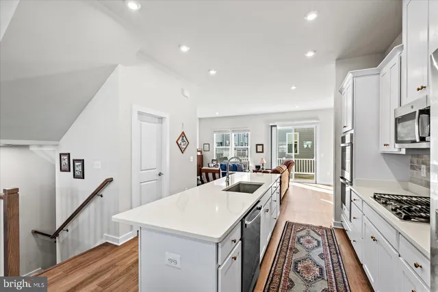 a kitchen with stainless steel appliances a sink a stove top oven a chimney and a center island