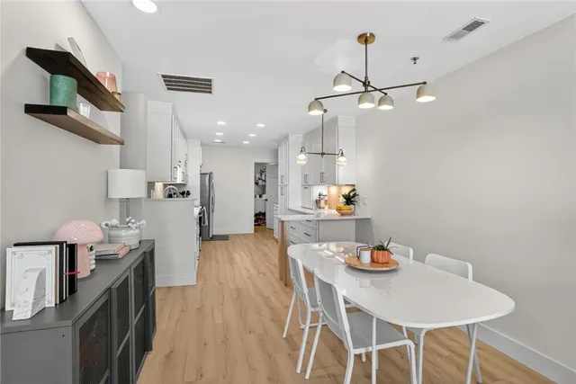 a kitchen with stainless steel appliances kitchen island granite countertop a table chairs and a refrigerator
