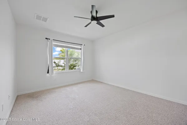 an empty room with windows and ceiling fan view