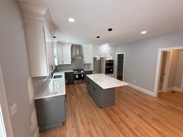 a large kitchen with stainless steel appliances a large counter top a sink a refrigerator and a window