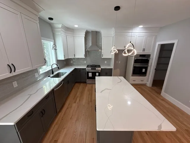 a large kitchen with stainless steel appliances a large counter top a stove a sink a refrigerator and a cabinets