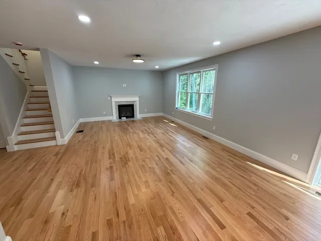 a view of empty room with wooden floor and fireplace