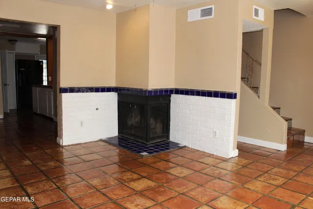 a view of an empty room with window and chandelier fan
