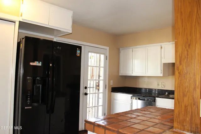 a kitchen with granite countertop white cabinets and black appliances
