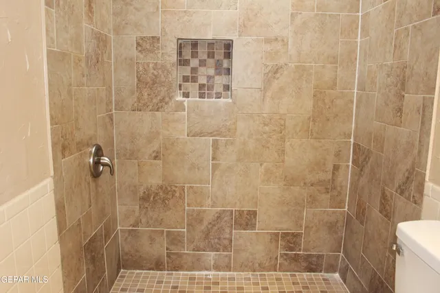 a bathroom with a sink a toilet a shower and a window