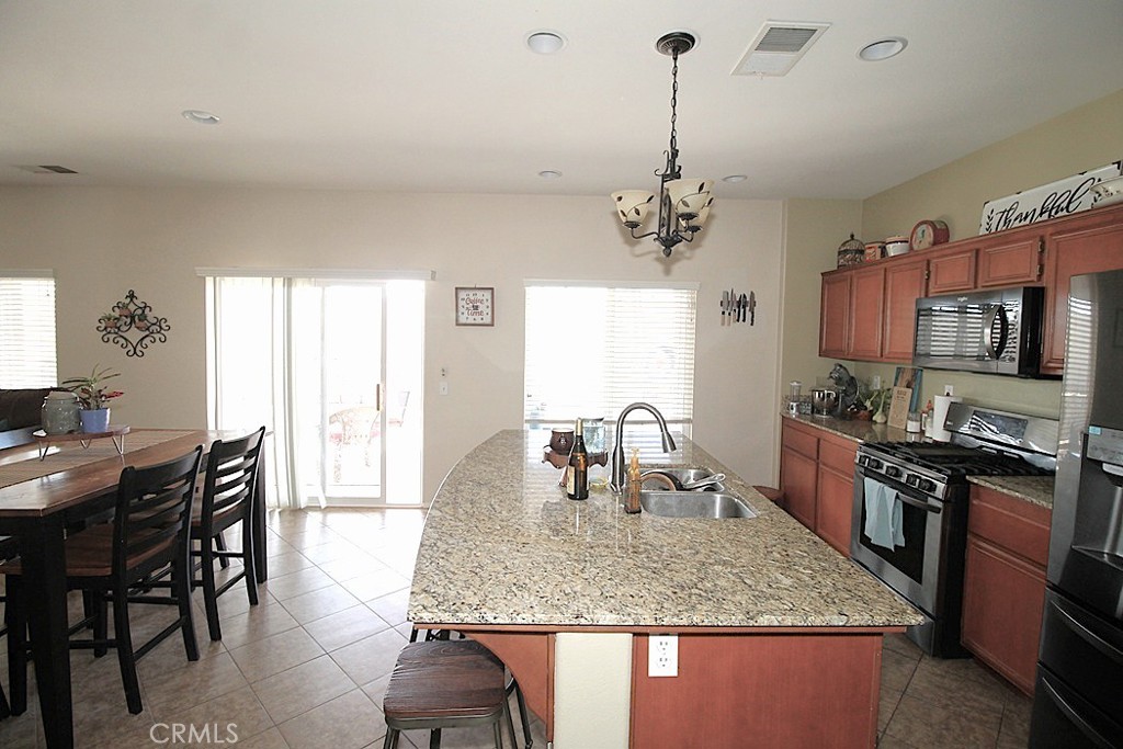 924 Condor Street Barstow, CA 92311 - Photo 19 of 52 a kitchen with stainless steel appliances granite countertop a stove top oven a dining table and chairs with wooden floor