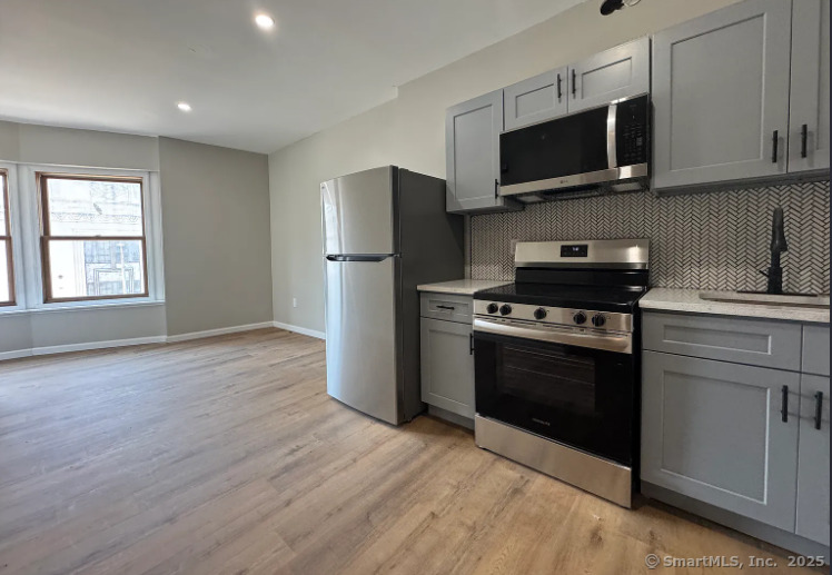 61 Field Street, Unit 211 Waterbury, CT 06702 - Photo 2 of 11 a kitchen with stainless steel appliances a stove a microwave and white cabinets