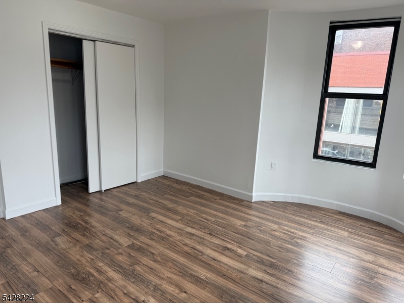 182 Ferry Street, Unit 2F Newark, NJ 07105 - Photo 13 of 14 a view of an empty room with wooden floor and a window
