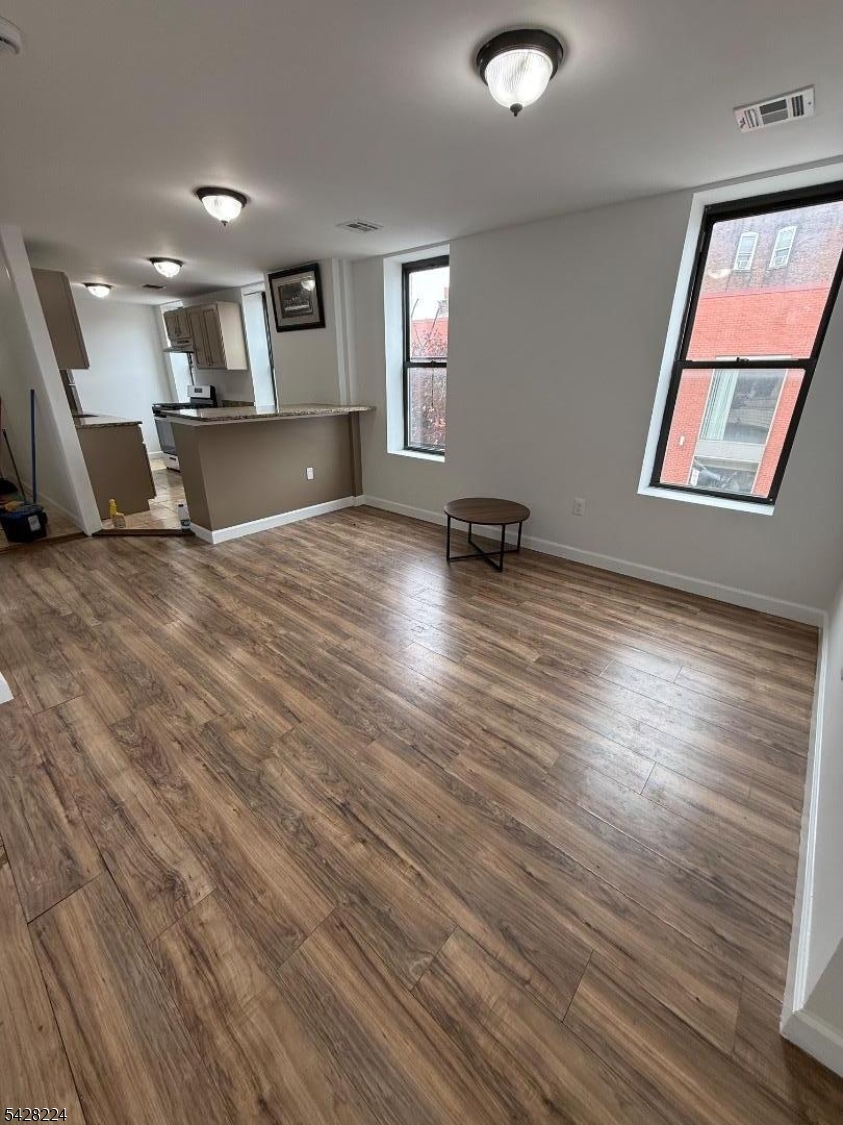 182 Ferry Street, Unit 2F Newark, NJ 07105 - Photo 2 of 14 an empty room with wooden floor and windows