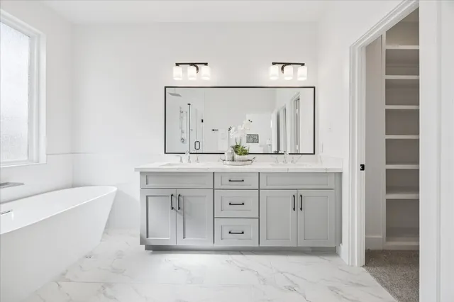 a spacious bathroom with a double vanity sink a mirror and a bathtub