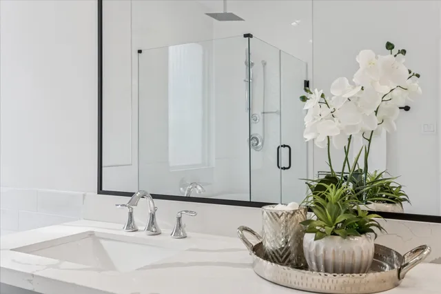 a bathroom with a granite countertop sink a mirror and a shower