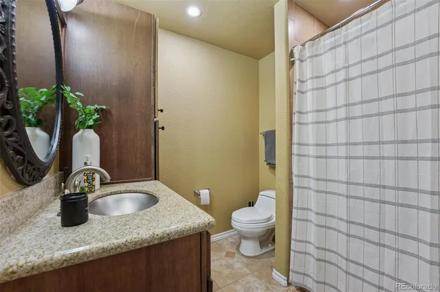 a bathroom with a granite countertop sink a toilet and mirror