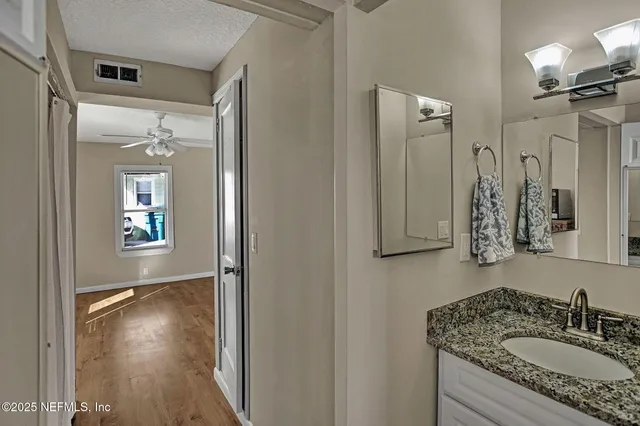a bathroom with a granite countertop sink a mirror and shower