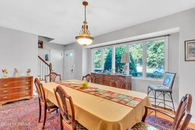 a dining room with wooden floor a chandelier a wooden table and chairs