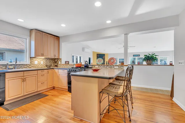 a open kitchen with stainless steel appliances granite countertop a stove a sink a refrigerator cabinets and a dining table with wooden floor