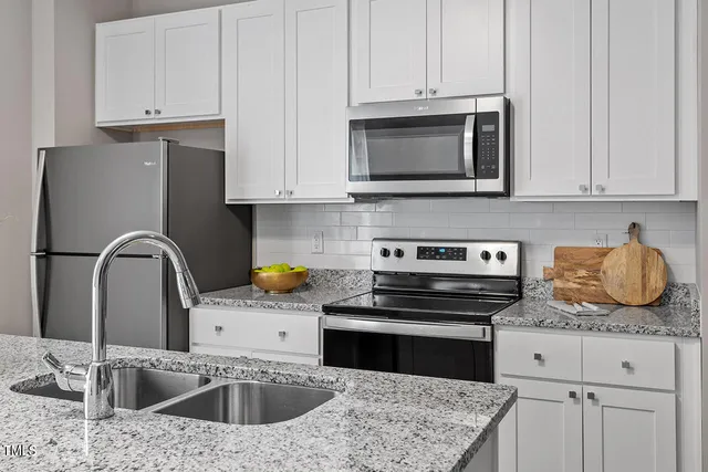 a kitchen with granite countertop a stove a sink and a microwave