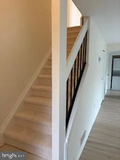 a view of staircase with lots of frames on wall and wooden floor