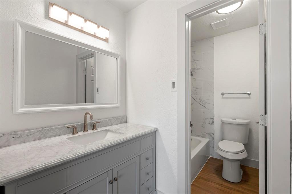 4247 Madera Road Irving, TX 75038 - Photo 21 of 28 a bathroom with a granite countertop toilet sink and a mirror