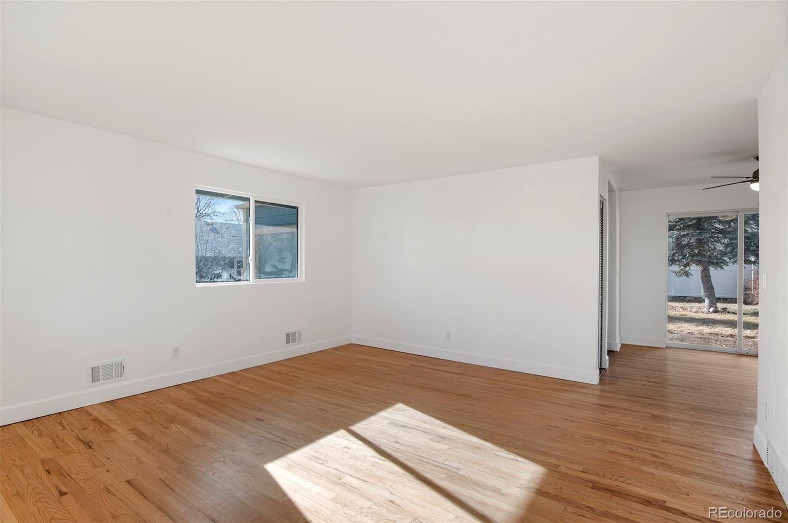 7483 Knox Court Westminster, CO 80030 - Photo 11 of 35 an empty room with wooden floor and windows
