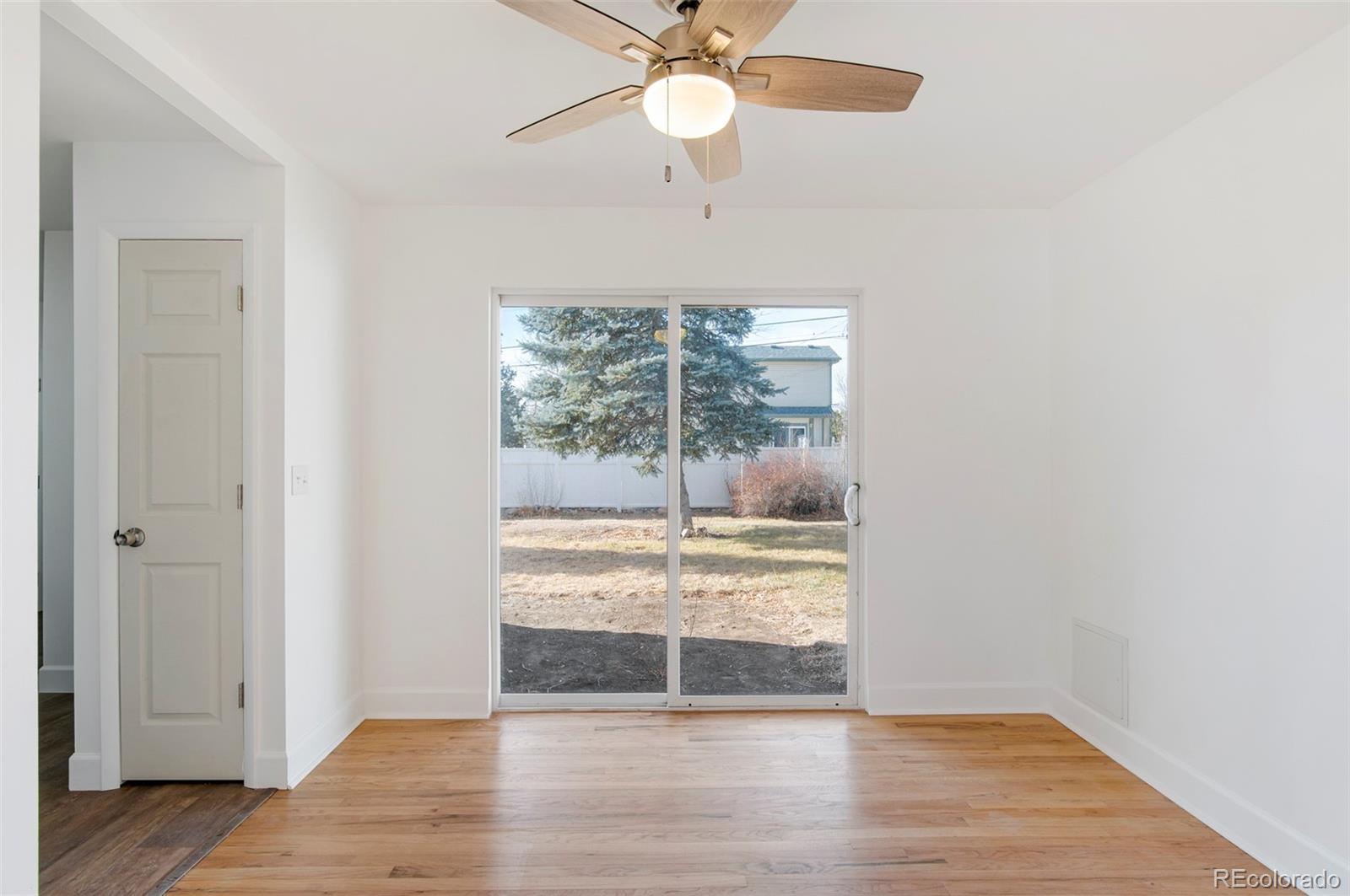 7483 Knox Court Westminster, CO 80030 - Photo 12 of 35 an empty room with wooden floor fan and windows