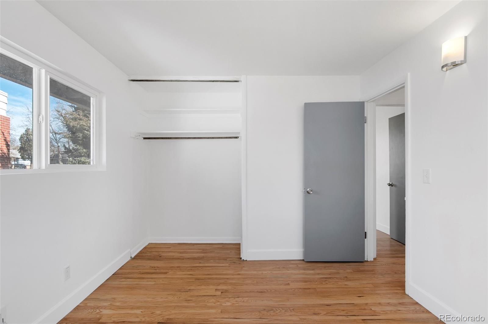 7483 Knox Court Westminster, CO 80030 - Photo 19 of 35 a view of an empty room with wooden floor and a window