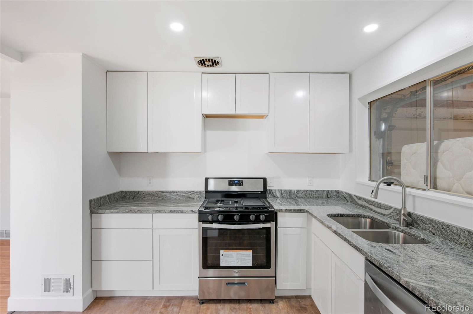 7483 Knox Court Westminster, CO 80030 - Photo 22 of 35 a kitchen with granite countertop a sink stove and cabinets