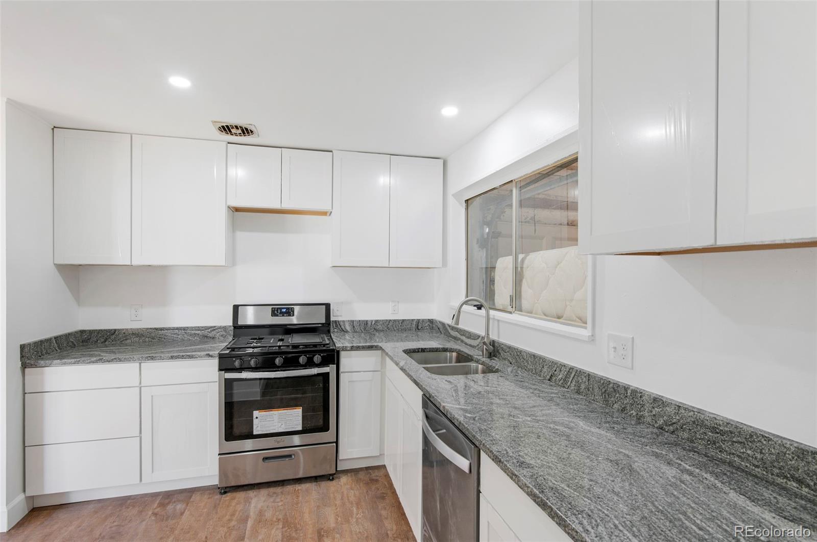 7483 Knox Court Westminster, CO 80030 - Photo 23 of 35 a kitchen with granite countertop a sink stainless steel appliances and cabinets