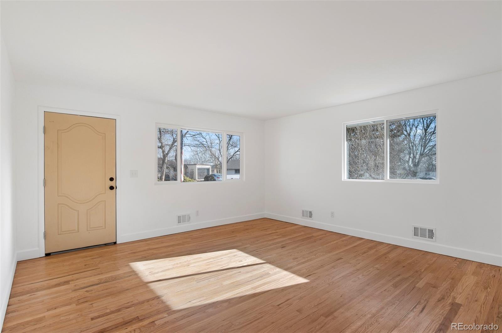 7483 Knox Court Westminster, CO 80030 - Photo 8 of 35 a view of an empty room with wooden floor and a window