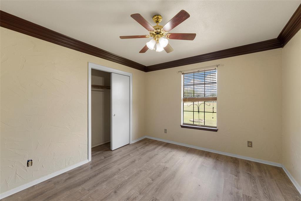3433 West Tours Road West, TX 76691 - Photo 26 of 40 Unfurnished bedroom featuring ornamental molding, light wood finished floors, a textured wall, a ceiling fan, and a closet