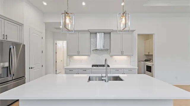 a kitchen with a white center island and stainless steel appliances