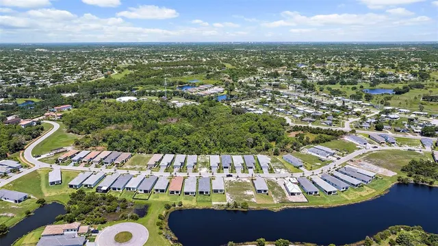 an aerial view of a city with lots of residential buildings ocean and mountain view in back