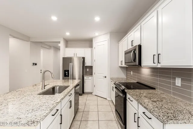 a kitchen with stainless steel appliances granite countertop a sink stove and refrigerator