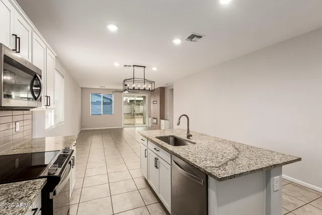 a kitchen with granite countertop stainless steel appliances a sink stove and cabinets